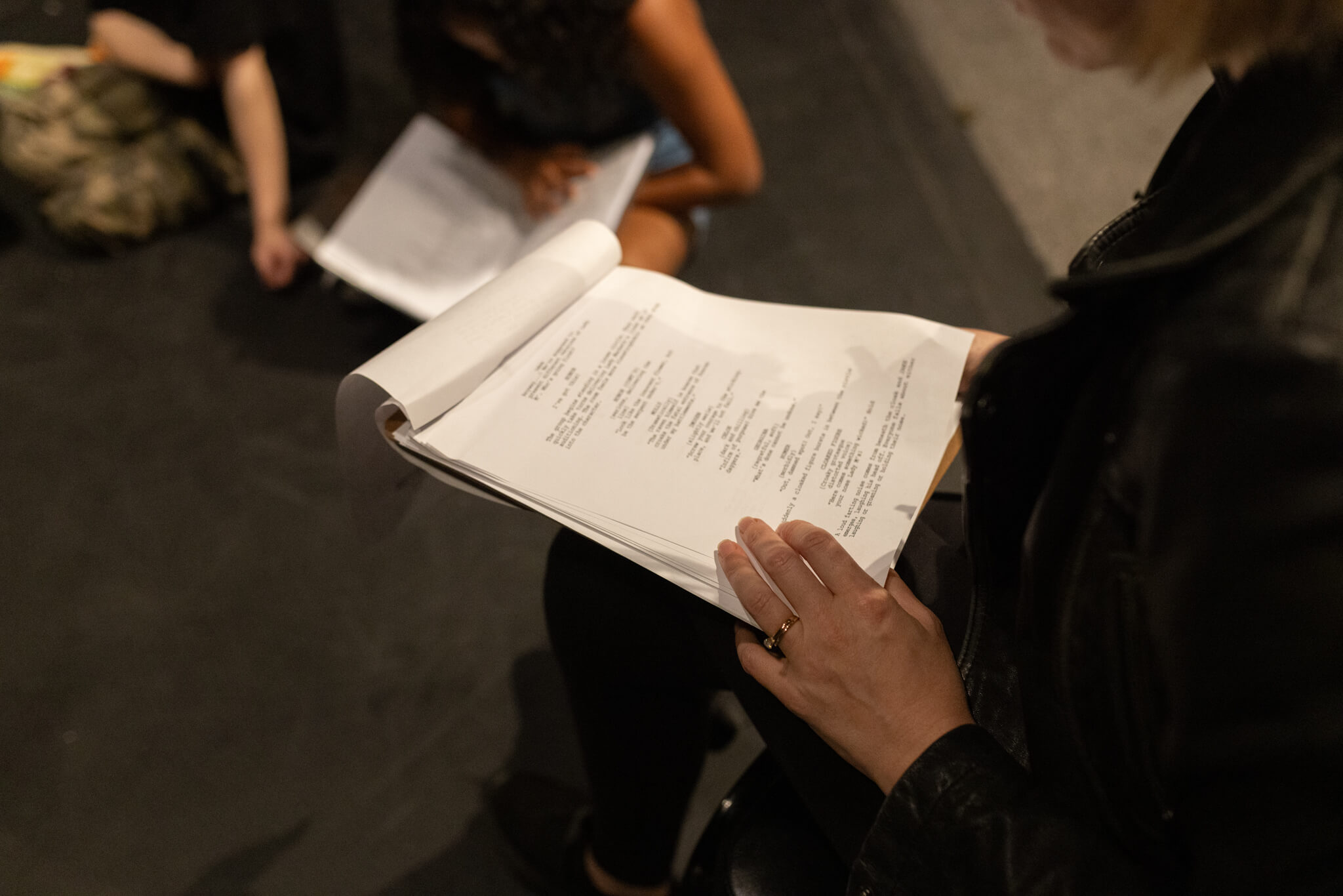 A peek over a woman's shoulder as she reads a script on a theatre stage